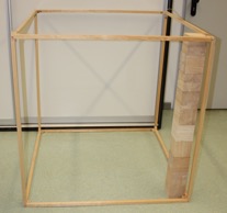 Foto einer Holzkonstruktion zum Aufbau von Vorstellungen zu Volumina. Darin sind 10 Tausenderwürfel übereinandergestapelt. In die Holzkonstruktion müssten also schätzungsweise 10 mal 10 Tausenderwürfel passen.