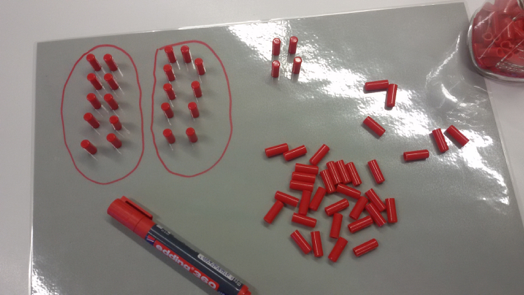 Foto zum Zählen von Bonbons. Rechts: Unstrukturierter Haufen an Bonbons. Links: Hier wurden jeweils 10 Bonbons auf Pappe gelegt und mit einem Stift eingekreist.